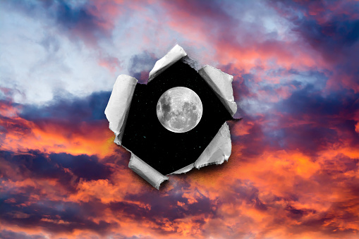 A hole in the sunset sky with torn edges, as if on paper, overlooking the night sky with a full moon and stars. The concept of global climate change on Earth, global warming, a hole in space and time.