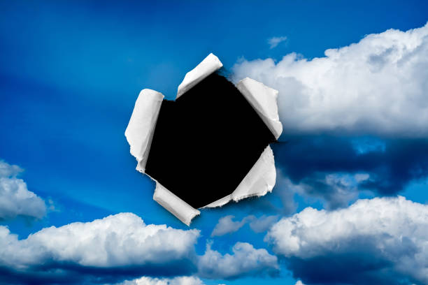 istock A hole in the day sky with torn edges, as on paper, with an isolated black copyspace background in the center. The concept of global climate change on Earth, global warming, a hole in space and time. 1222181819
