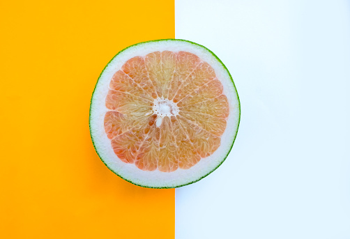 Top view of a one pomelo slice on two color white and yellow background, sweetie citrus fruit, Fresh and colorful