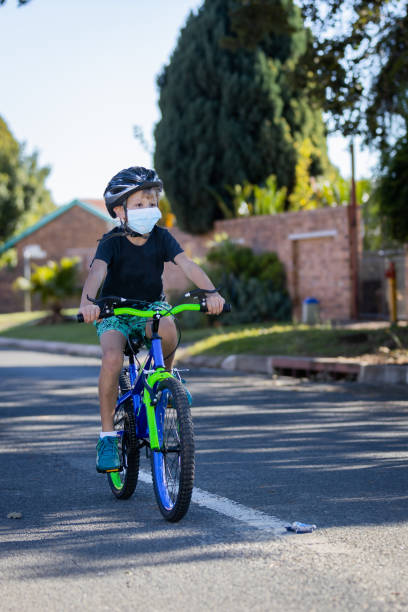 istock boy cycling in suburb wearing a mask 1222183738