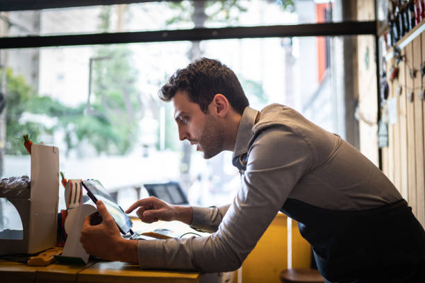 Small business owner using digital tablet at his store Small business owner using digital tablet at his store point of sale tablet stock pictures, royalty-free photos & images