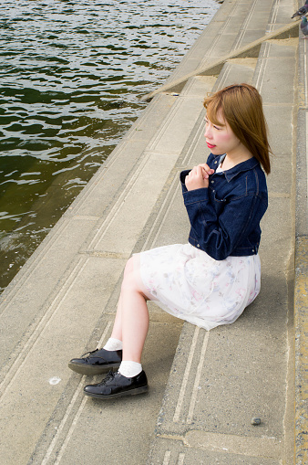 A woman sitting on the shore of the Tama River