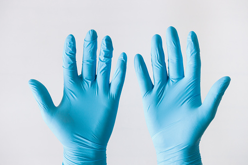 Hands of a medic in the blue latex gloves on white background.
Protection against bacteria and viruses concept.