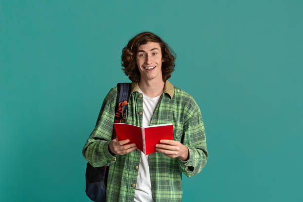 istock Back to school. Happy student with open notebook and backpack on turquoise background 1222186791