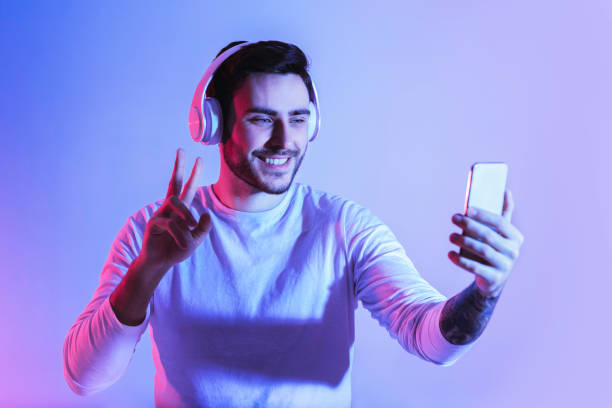 istock Smiling guy showing peace sign in smartphone 1222187442