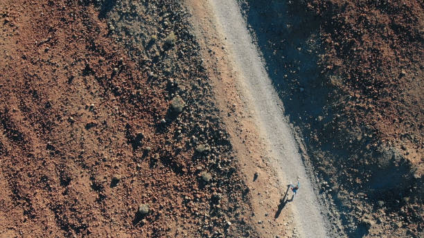 vue d’en haut. une femme court le long du chemin dans les montagnes, autour du sable volcanique et de la lave gelée - el teide national park photos et images de collection