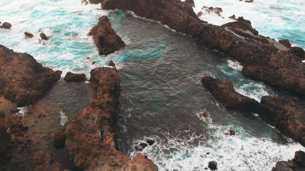 aerial view from afar - a person stands on the edge of a rock of volcanic origin, the ocean coast. tenerife, spain - waters edge wave beach soap sud imagens e fotografias de stock