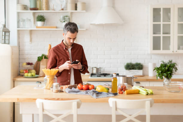 istock Man  look for recipe at phone preparing dinner 1222189230