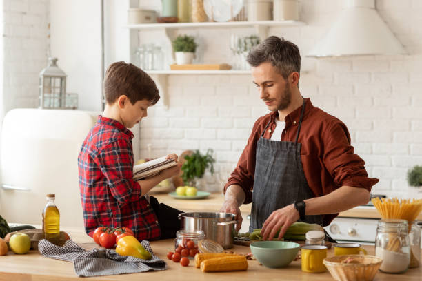 istock Father son cooking together by recipe in cookbook 1222189311