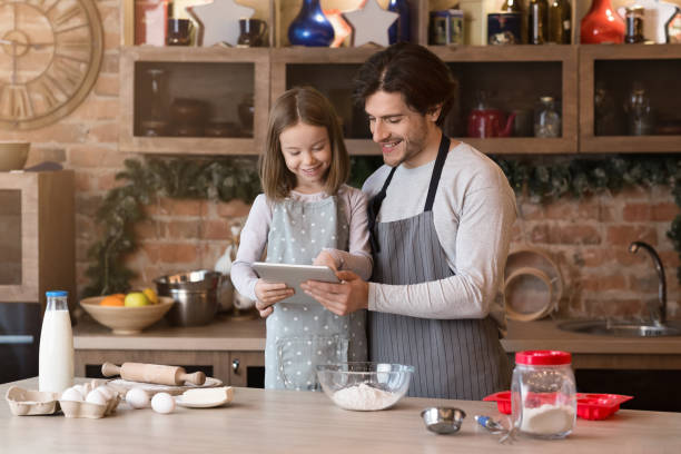 istock Dad And Daughter Using Digital Tablet Following Recipe To Prepare Dough 1222189322