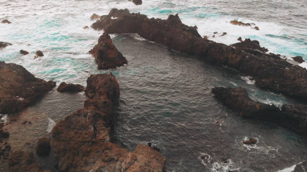 the man on the edge of the world aerial. the shore of volcanic origin, rocks in the ocean, shots from the drone. - waters edge wave beach soap sud imagens e fotografias de stock