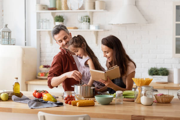 feliz madre y padre viendo cocina hija - cooking men caucasian togetherness fotografías e imágenes de stock