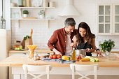 Man and woman laughing cook dinner on kitchen