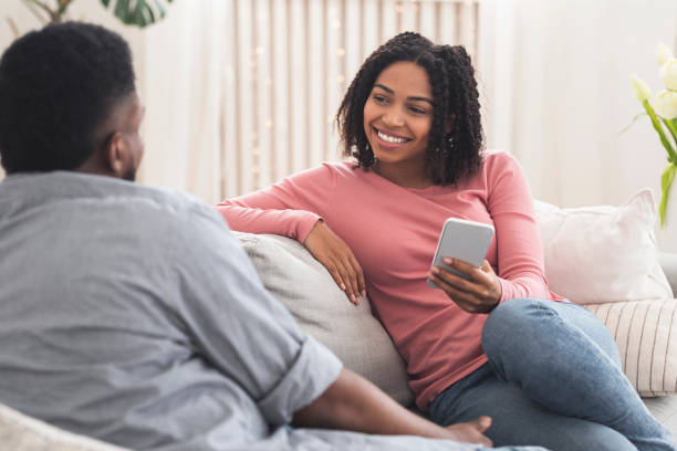 istock Young african couple chatting at home, relaxing on sofa together 1222192102