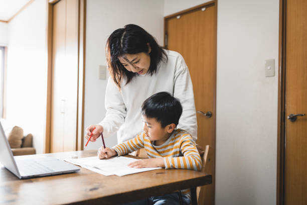 istock Boy taking an e-Learning course with laptop and his mother watching it 1222192820