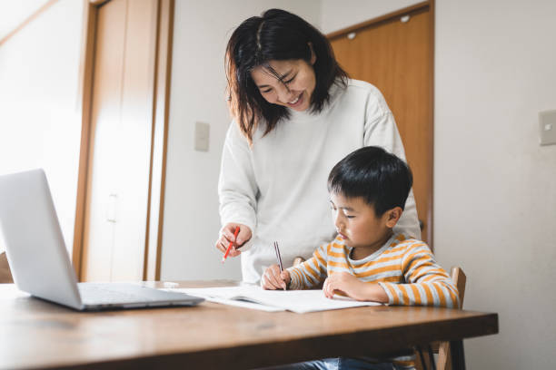 istock Boy taking an e-Learning course with laptop and his mother watching it 1222192823