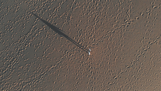 Top-down view - attractive girl walks through the desert. Lots of footprints in the sand at sunset, long female shadow. Aerial, Maspalomas, Gran Canaria 2k