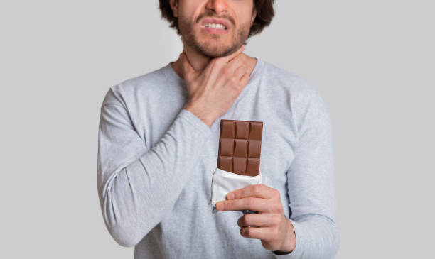istock Allergic to chocolate. Man feels bad, holding his throat 1222194309