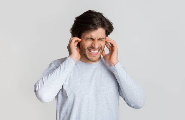 istock Ear pain concept. Guy grimaces and touches ears 1222194472