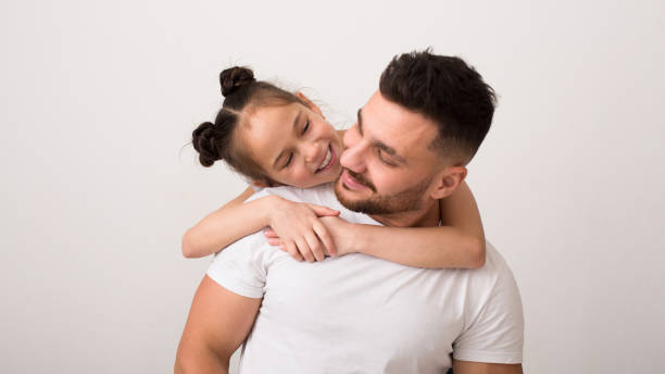 istock Loving girl embracing her daddy, white studio background 1222194509