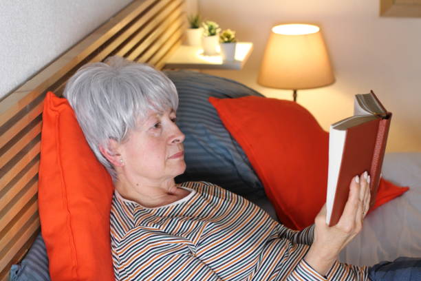 istock Senior woman reading book in bed 1222195439