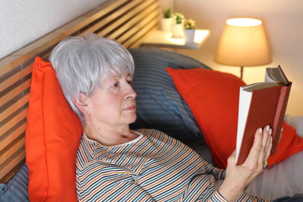 istock Senior woman reading book in bed 1222195523
