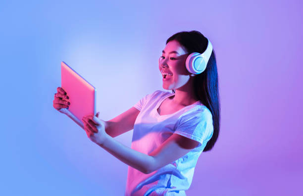 istock Woman in wireless headphones playing on tablet 1222195567