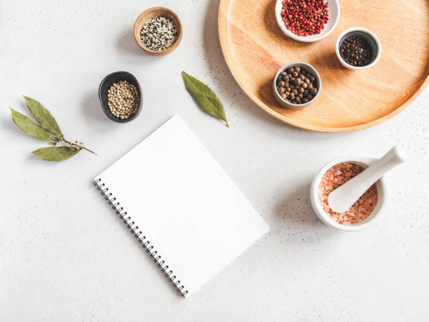 istock Kitchen notepad mock up for culinary text and various spices in bowl and sea salt in white mortar on white background. 1222196103