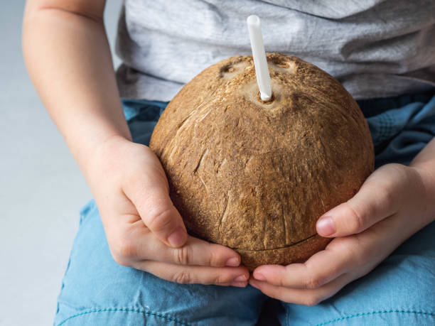 istock Uncertain child in blue shorts holds in his hands a young coconut with drinker 1222196201