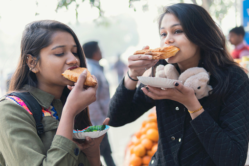 Indian girls eating street food. outdoor shoot. shoot location at Delhi Raj Ghat.