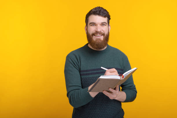 istock Bearded man looking at the camera is writing someting in his journal. 1222199959