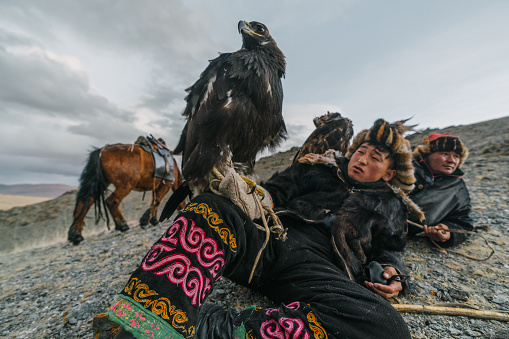 Eagle hunter resting in mountains in desert in Mongolia
