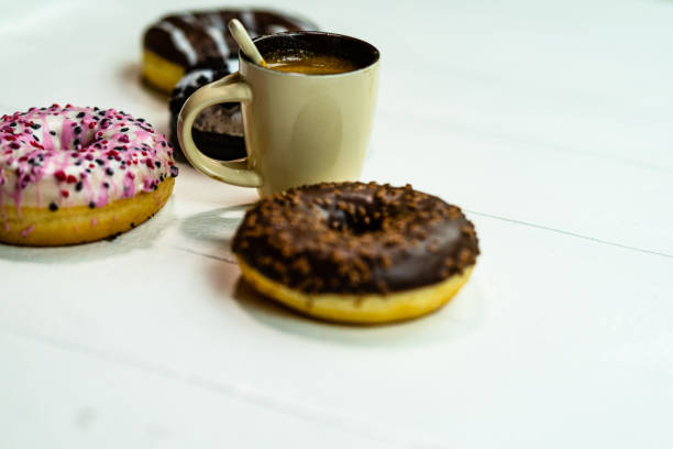 istock Colorful donuts and coffee cup on white wooden table. Sweet bakery with glazed sprinkles, breakfast concept. Top view with copy space 1222201876