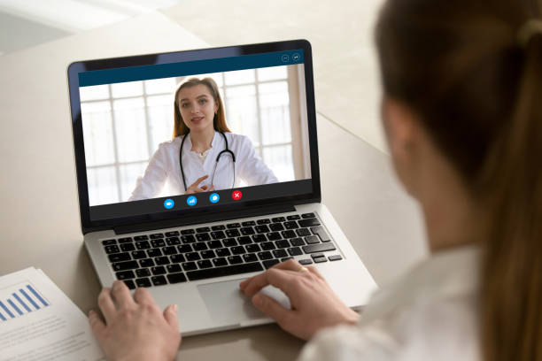 Young woman consulting with family therapist online via video call. Shoulder view young woman consulting with family therapist doctor general practitioner online via video call on laptop after feeling first virus illness symptoms, medical insurance, covid19 outspread. general view stock pictures, royalty-free photos & images