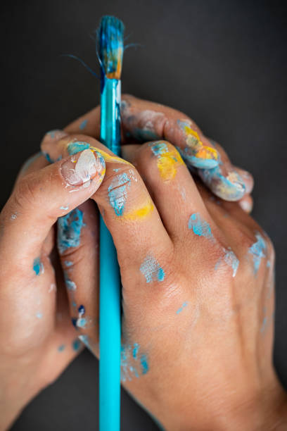 istock Paint-stained painters hands holding paintbrush 1222204523