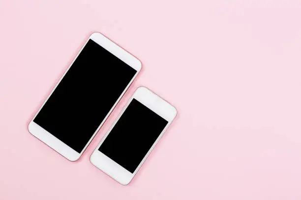 Two cellphones in different sizes on pink background. Small or big phone concept. Screens are mockups so it's easy to show responsive design on different devises.