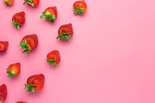 Ripe juicy strawberries on a pink background. pattern, Fresh berry flat lay. Creative Minimal food concept