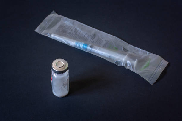 istock Disposable syringe in package and vial with white powder. Dark background. Horizontal. 1222206928
