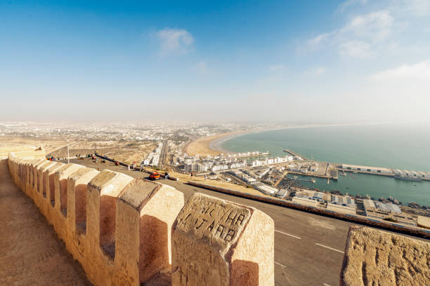 モロッコのオウフェラヒルの旧市街の壁から見た広いビーチと港を持つモダンなアガディール - agadir ストックフォトと画像
