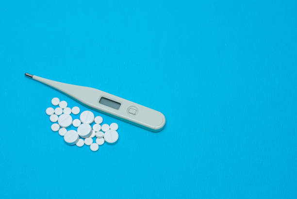 istock White pills and medical thermometer. 1222208500