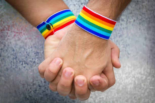 Men holding hands with rainbow-patterned wristband stock photo