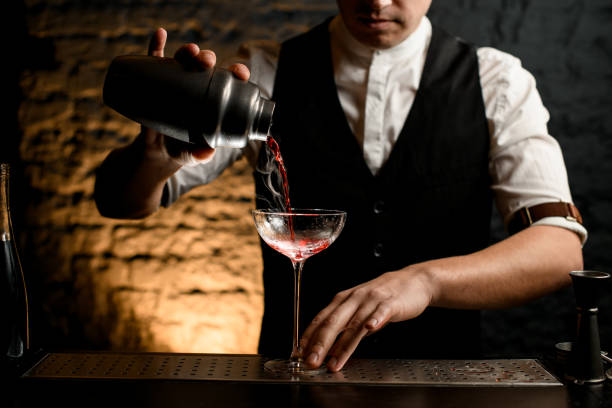 istock Close-up professional bartender pouring cocktail from stainless shaker into glass 1222213872