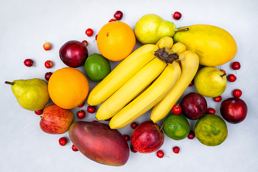 Fruit collection, creative layout seen from the top. Banana, apple, pear, orange, lemon, papaya, mango, acerola and plum, tropical fruits on isolated white background healthy eating