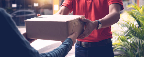 Delivery man by sending box of parcel to customers service at home as having corona virus disease or covid 19 spreading stock photo