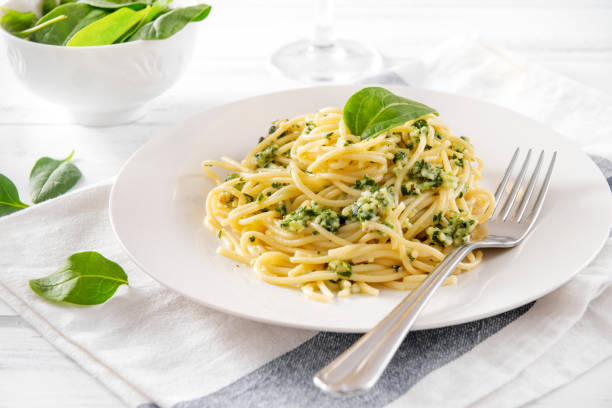 istock pasta with spinach and cheese on a plate, fork,  towel,  fresh spinach leaves on a light background 1222217526