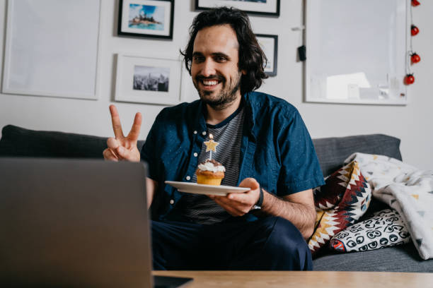 Man is celebrating his birthday "virtually" with his friends and relatives with a VoIP call Man is celebrating his birthday "virtually" with his friends and relatives with a VoIP call. He's at home during coronavirus Covid-19 quarantine. virtual birthday celebration stock pictures, royalty-free photos & images
