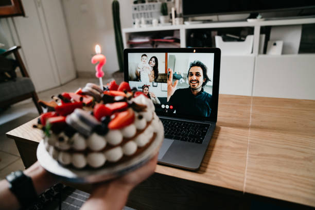 Young woman is celebrating her birthday with friends and relatives during quarantine Young woman is celebrating her birthday with friends and relatives during quarantine. She's doing a video call with laptop. virtual birthday celebration stock pictures, royalty-free photos & images