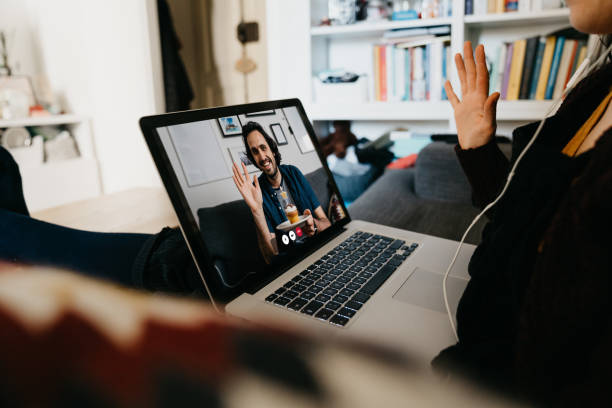 Man celebrating his birthday with a video call during quarantine Man celebrating his birthday with a video call during quarantine. A woman is celebrating with him via a VoIP call. virtual birthday celebration stock pictures, royalty-free photos & images