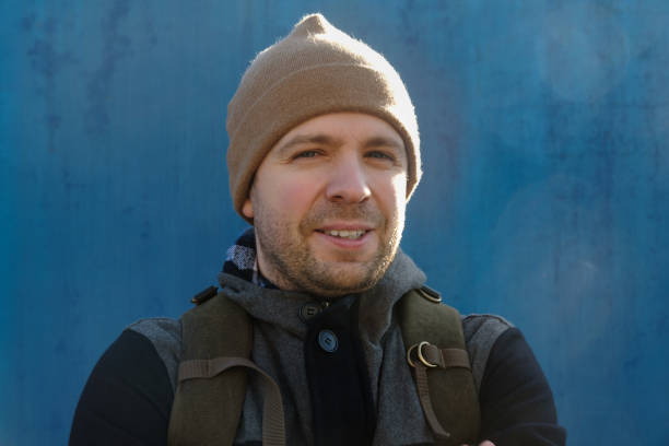 istock Handsome caucasian young man in hat and jacket outdoors on sunny day on blue wall 1222224384