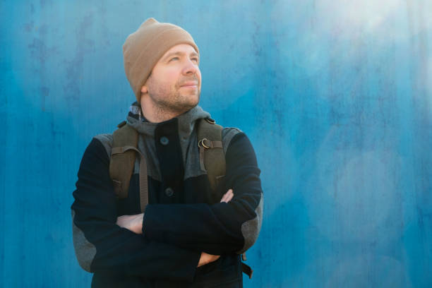 istock Handsome caucasian young man in hat and jacket outdoors on sunny day on blue wall 1222224403